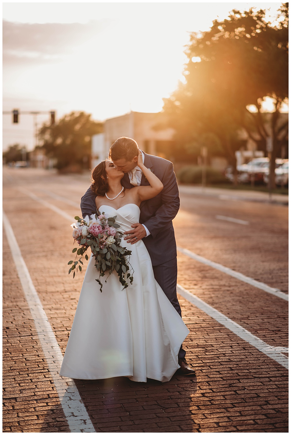 Husband and wife kiss in golden light by Three Feather Photography