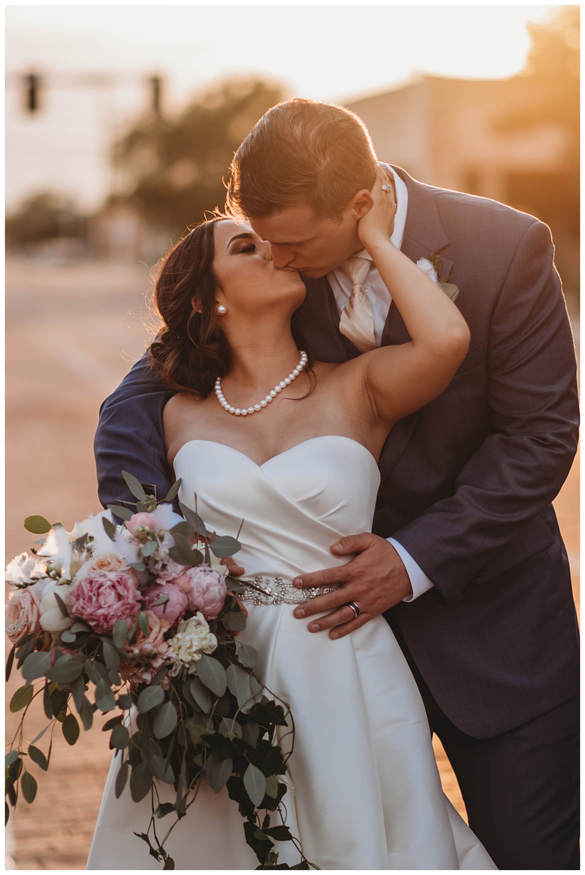 Newlyweds kiss in golden light on street at upscale Texas wedding