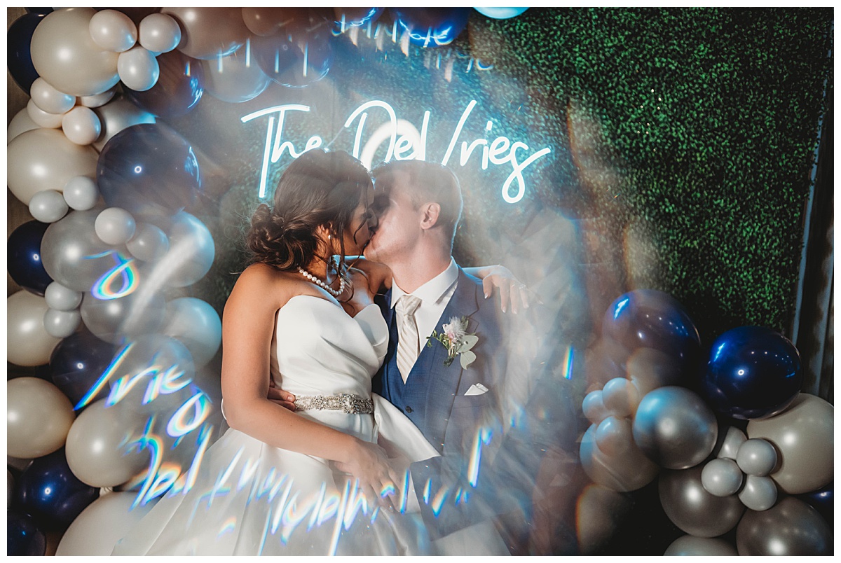Neon sign and balloons create backdrop at upscale Texas wedding