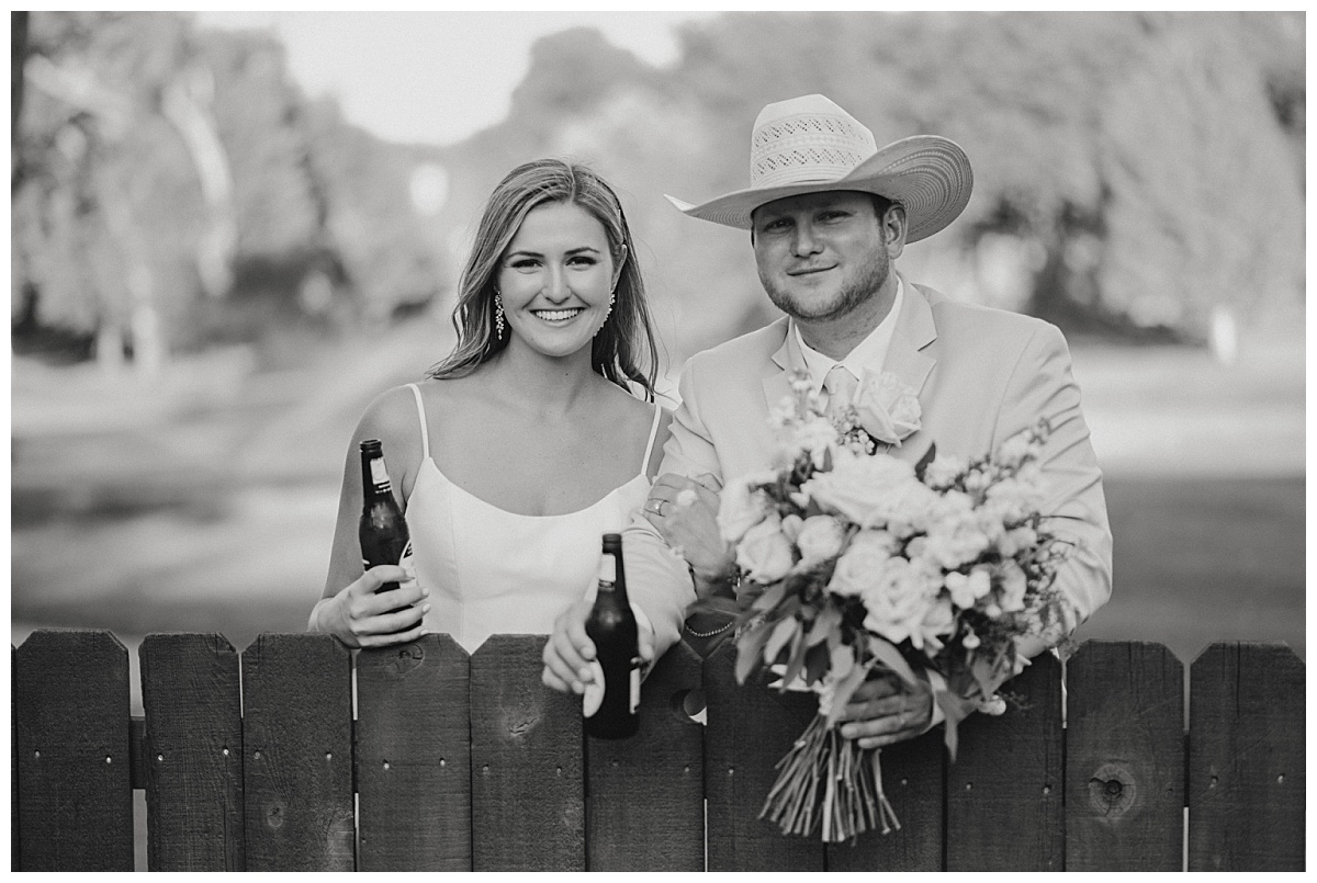 Couple leans on gate with drinks by Amarillo portrait photographer